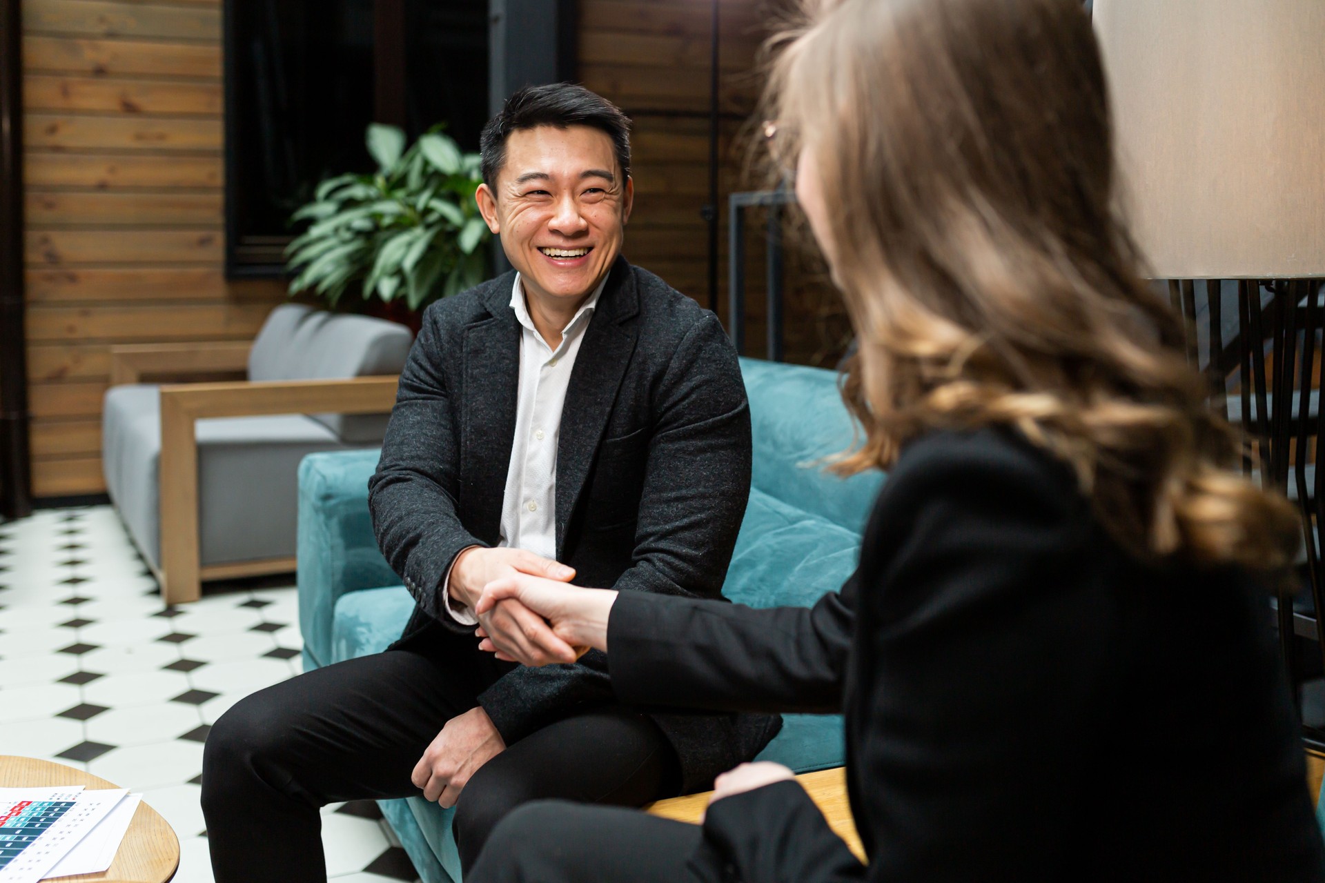 A man and a woman end a business meeting, shake hands, and rejoice in a successful deal